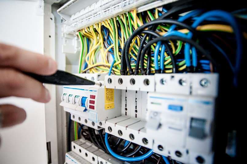 Electrician inspecting a distribution board with circuit breakers and wiring